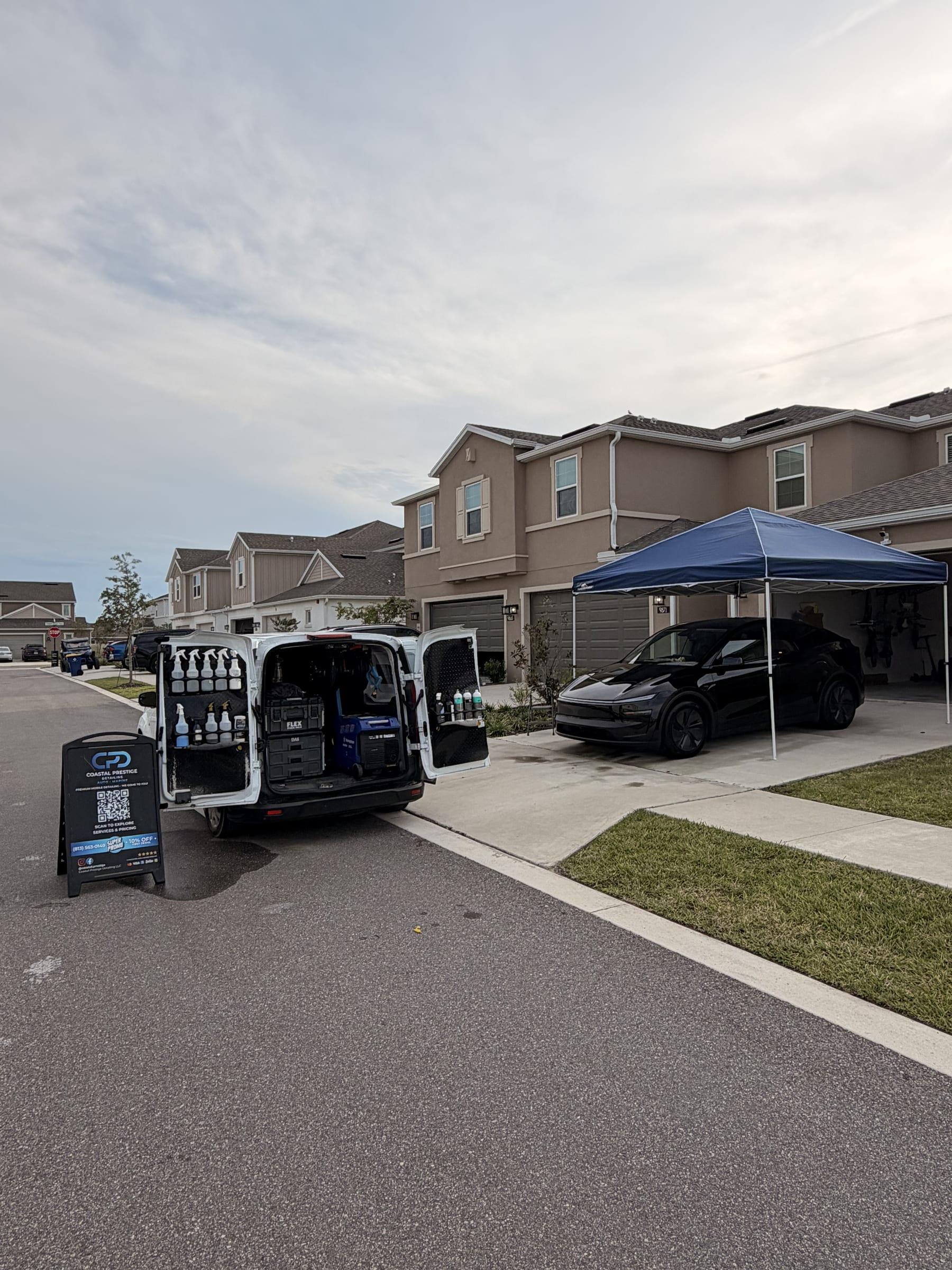 Coastal Prestige Detailing van open on a Wesley Chapel driveway with a canopy set up over a black Tesla Model Y